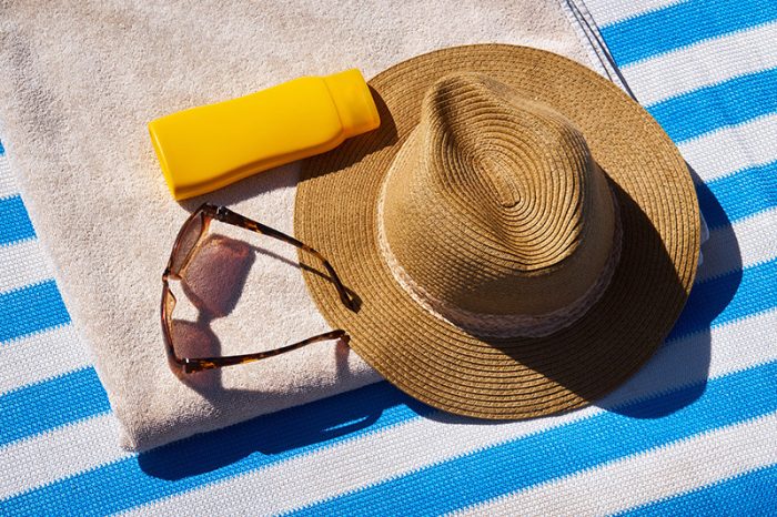 Hat, sunglasses, sunscreen, and beach towel