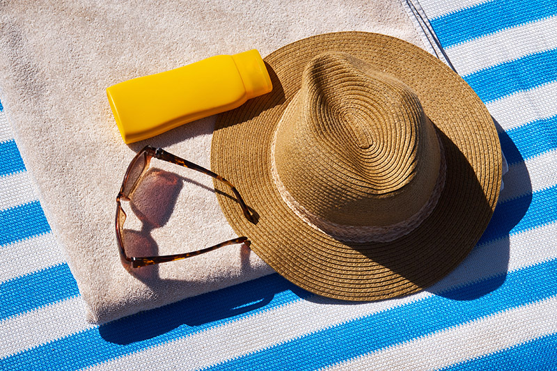 Hat, sunglasses, sunscreen, and beach towel