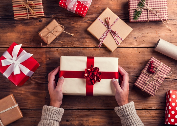 Person holding a wrapped gift, surrounded by other presents
