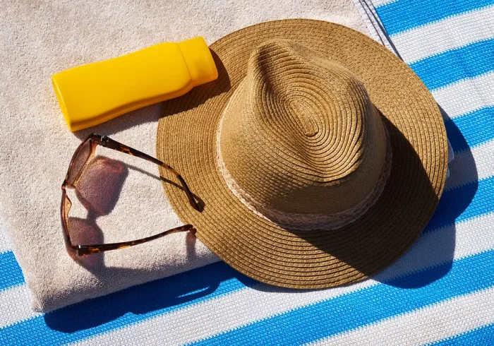 Hat, sunglasses, sunscreen, and beach towel